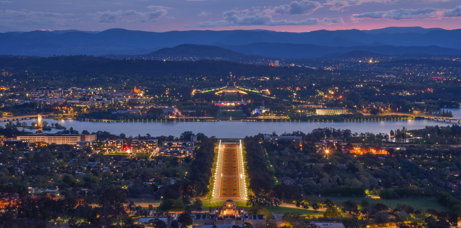 Canberra skyline at dusk over Lake Burley Griffin, Parliament House and ANZAC Parade